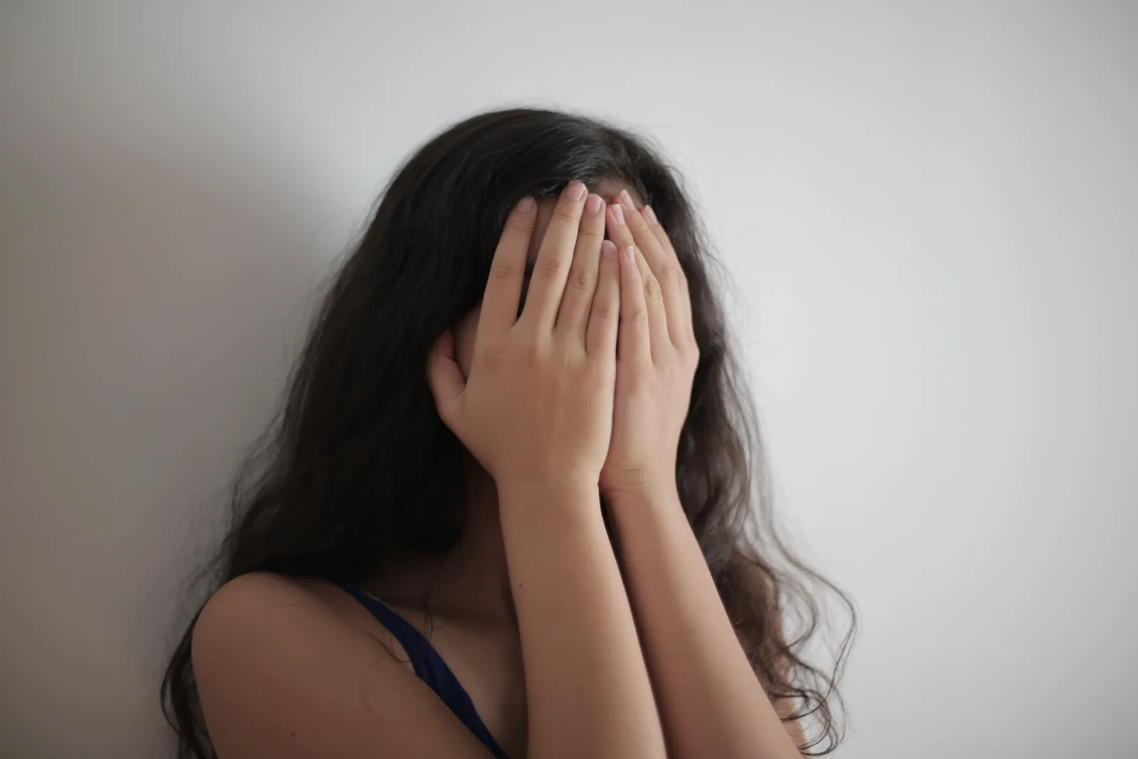 Visage d'une fille caché par ses mains