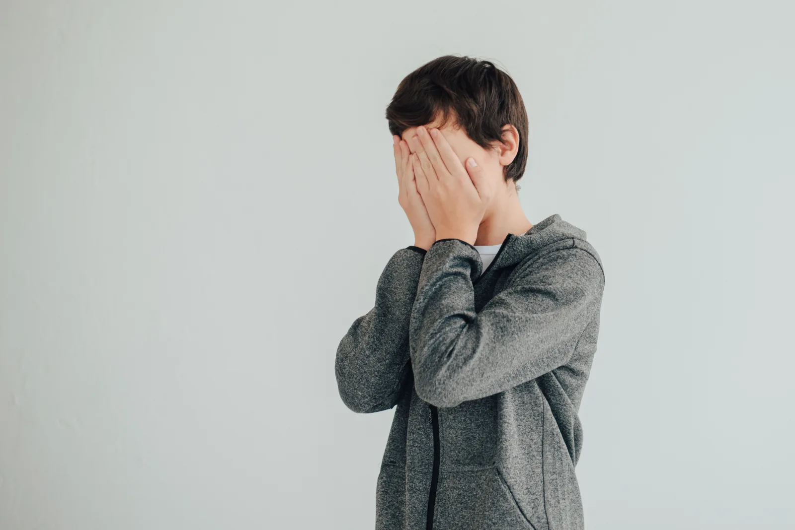 Garçon qui cache son visage avec ses mains